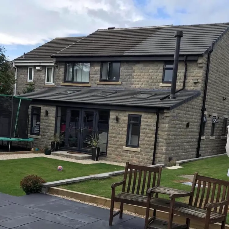 a house with a lawn and two wooden benches in front of it